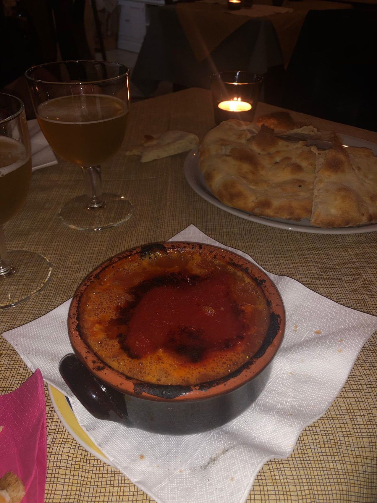 Un tavolo a lume di candela con il tegamino di terracotta e un calice di vino